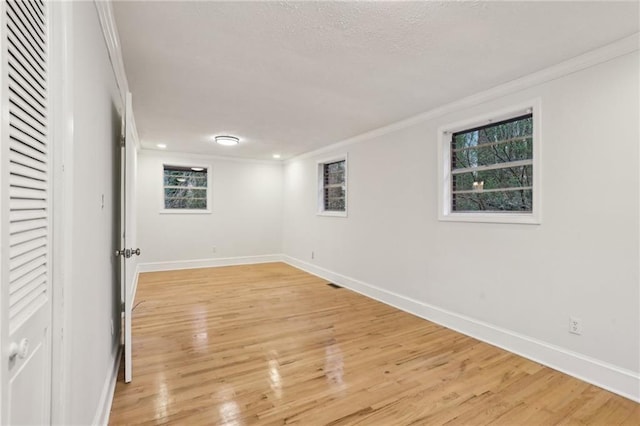 empty room featuring light wood-style floors, baseboards, and ornamental molding