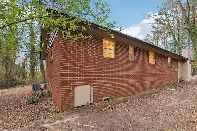 view of home's exterior featuring central AC unit, brick siding, and a chimney