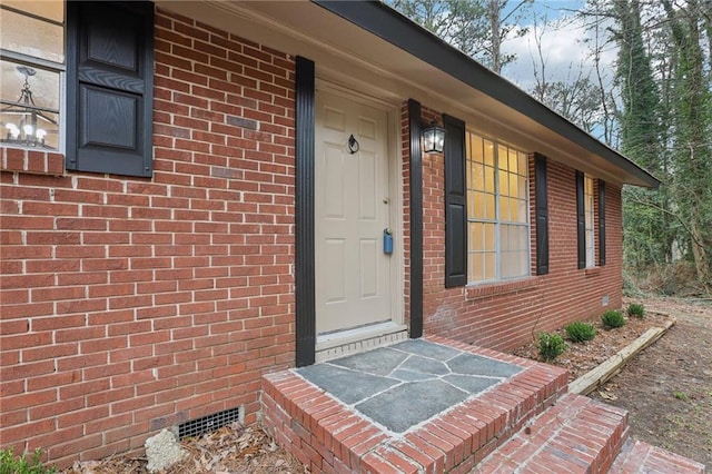 entrance to property featuring brick siding and crawl space