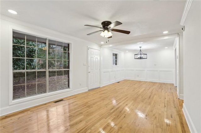 interior space featuring visible vents, ceiling fan with notable chandelier, light wood-type flooring, and crown molding