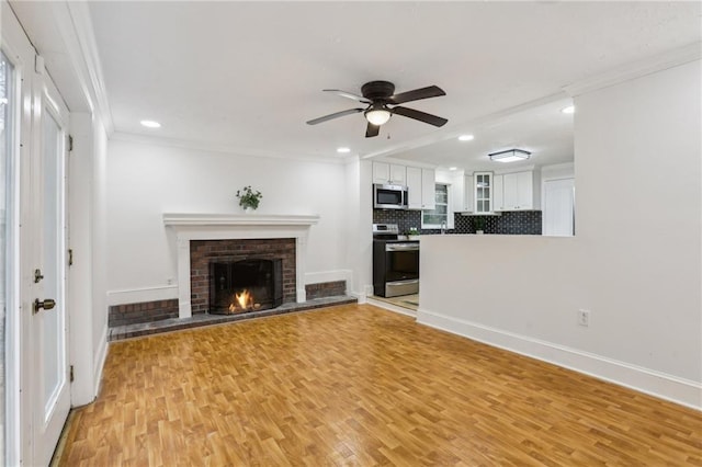 unfurnished living room featuring baseboards, light wood-type flooring, ceiling fan, and ornamental molding