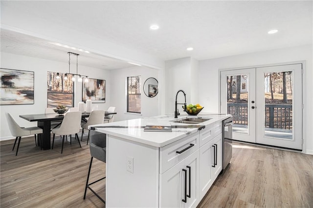 kitchen featuring sink, white cabinetry, hanging light fixtures, an island with sink, and stainless steel dishwasher