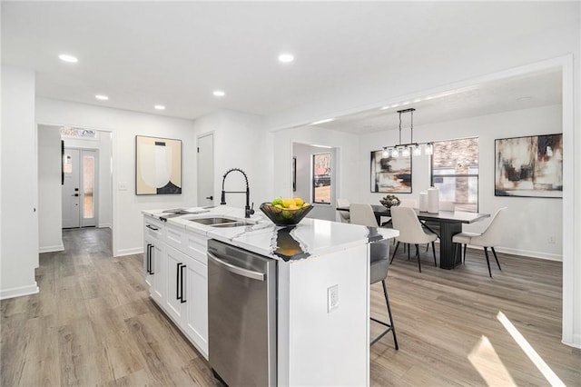 kitchen featuring white cabinetry, sink, a kitchen breakfast bar, a kitchen island with sink, and stainless steel dishwasher