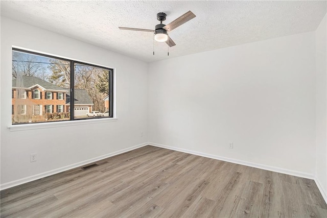 empty room featuring wood-type flooring, ceiling fan, and a textured ceiling