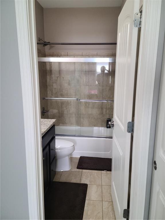 full bathroom with tile floors, combined bath / shower with glass door, toilet, and vanity