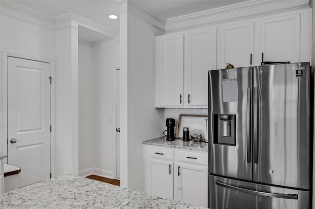 kitchen with stainless steel refrigerator with ice dispenser, white cabinetry, crown molding, and light stone counters