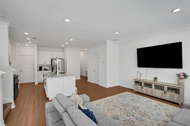 living room featuring crown molding, sink, and hardwood / wood-style floors