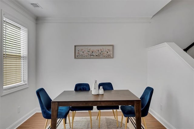 dining space featuring a wealth of natural light, ornamental molding, and wood-type flooring