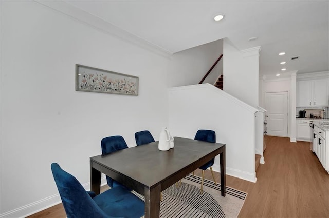 dining area with crown molding and light wood-type flooring