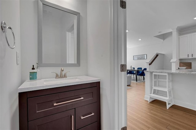 bathroom with crown molding, sink, and hardwood / wood-style floors