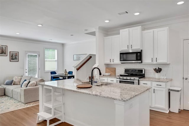 kitchen featuring stainless steel appliances, white cabinetry, sink, and a center island with sink