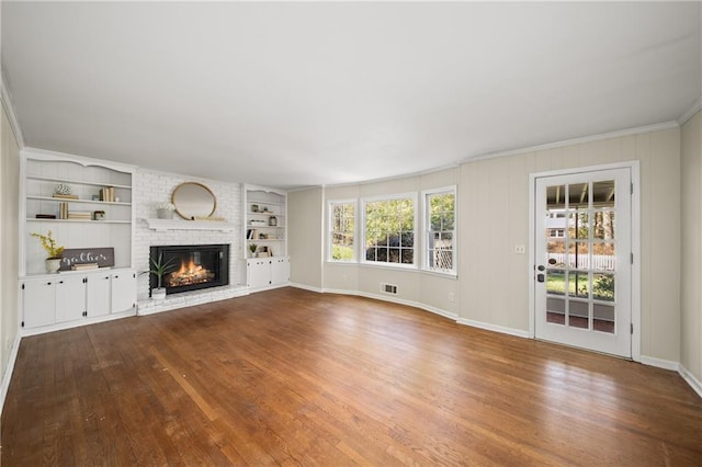 unfurnished living room with built in shelves, a fireplace, ornamental molding, wood finished floors, and baseboards