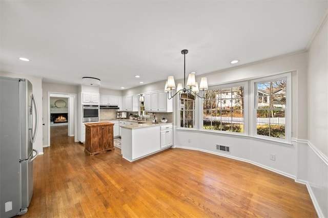 kitchen with light wood finished floors, visible vents, white cabinets, appliances with stainless steel finishes, and light countertops