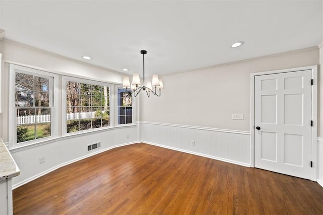 unfurnished dining area with dark wood-style flooring, a wainscoted wall, recessed lighting, visible vents, and a chandelier