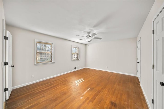 unfurnished bedroom with dark wood-type flooring, visible vents, baseboards, and a ceiling fan