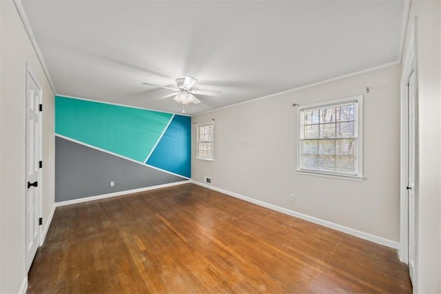 spare room with ceiling fan, wood finished floors, visible vents, baseboards, and ornamental molding