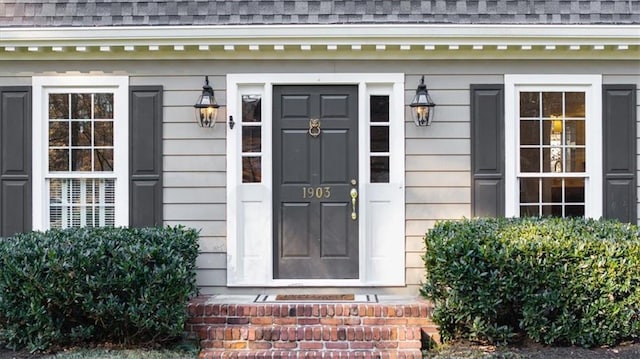 doorway to property with roof with shingles