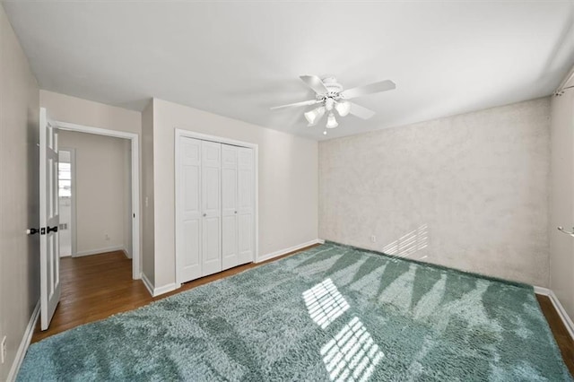 unfurnished bedroom with a ceiling fan, baseboards, dark wood finished floors, and a closet