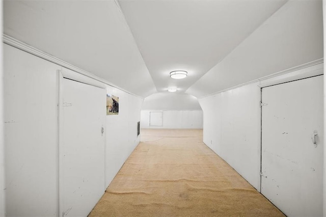 hall with lofted ceiling and light colored carpet