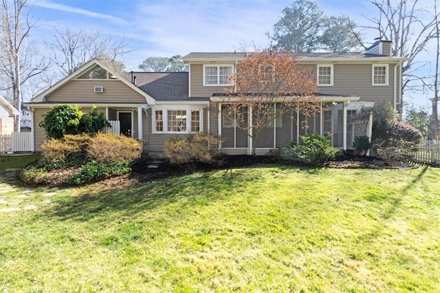 rear view of house featuring a lawn, a chimney, and fence