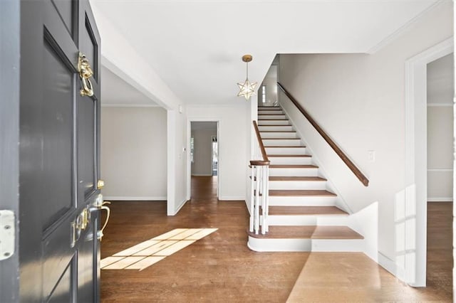 foyer with ornamental molding, dark wood-style flooring, baseboards, and stairs