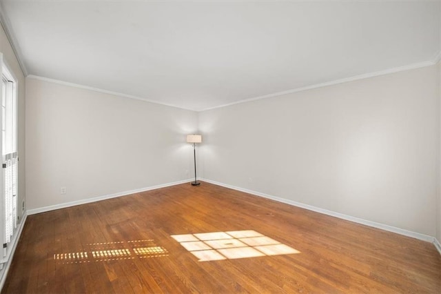 empty room with crown molding, baseboards, and wood finished floors