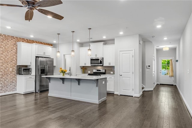 355 Niles Ct Unit 2, Marietta, GA 30060 - kitchen with decorative backsplash, a breakfast bar, light countertops, white cabinetry, and stainless steel appliances
