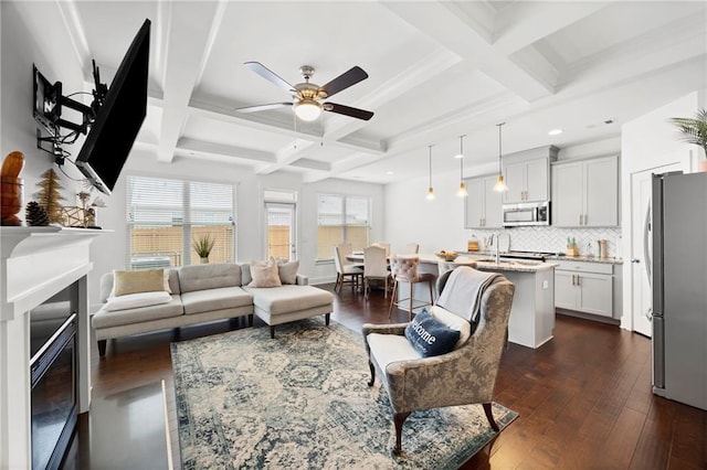 living room featuring beamed ceiling, dark hardwood / wood-style floors, ceiling fan, and coffered ceiling