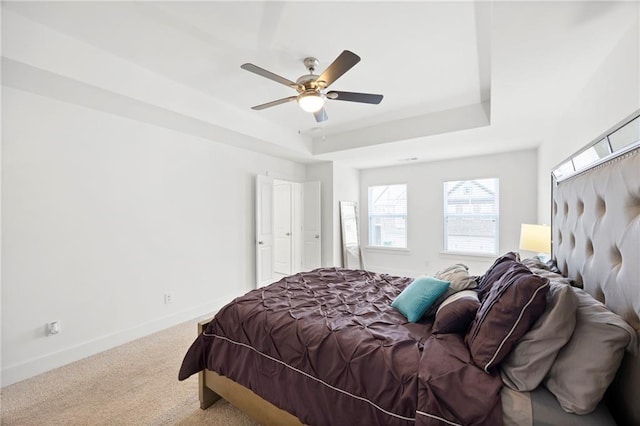 bedroom with carpet, a tray ceiling, and ceiling fan