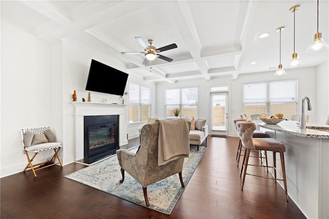 living room featuring ceiling fan, plenty of natural light, beamed ceiling, and sink