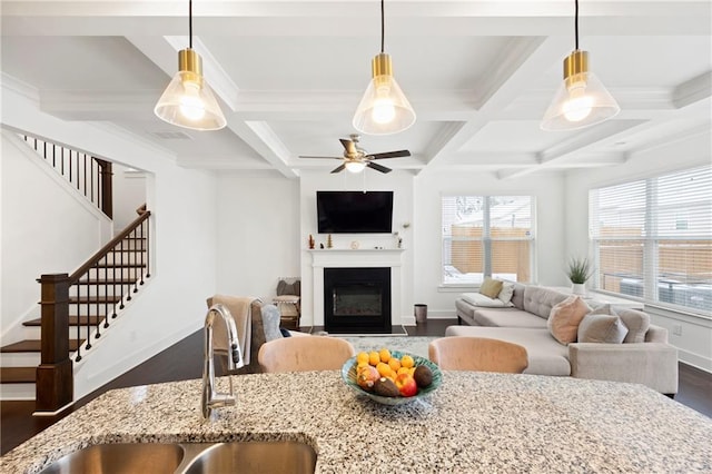 living room with beam ceiling, plenty of natural light, coffered ceiling, and sink