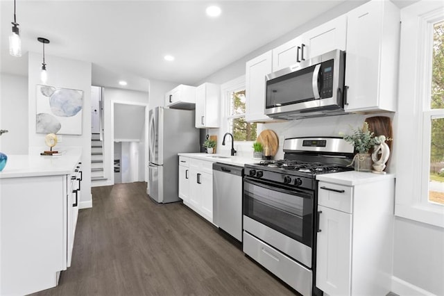 kitchen featuring white cabinets, appliances with stainless steel finishes, and decorative light fixtures