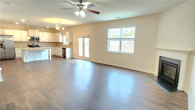 unfurnished living room with ceiling fan with notable chandelier and dark hardwood / wood-style floors