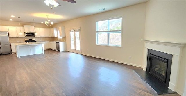 kitchen featuring appliances with stainless steel finishes, dark wood-type flooring, white cabinets, a center island, and hanging light fixtures