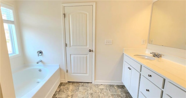 bathroom with a wealth of natural light, a washtub, and vanity