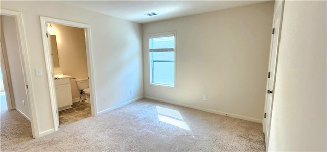 unfurnished bedroom with light carpet and ensuite bathroom