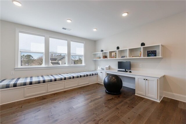 office with dark wood-type flooring and built in desk