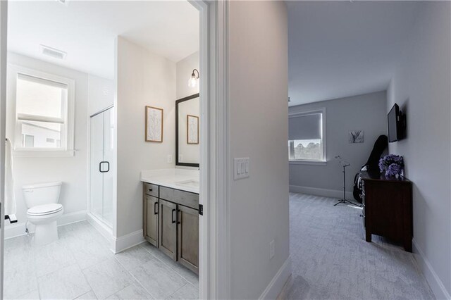 bathroom with a shower with door, vanity, and toilet