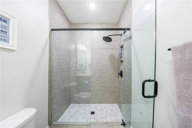 bathroom featuring vanity, a shower with shower door, tile patterned floors, and toilet