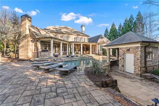 pool featuring a patio area, an outdoor structure, and a hot tub