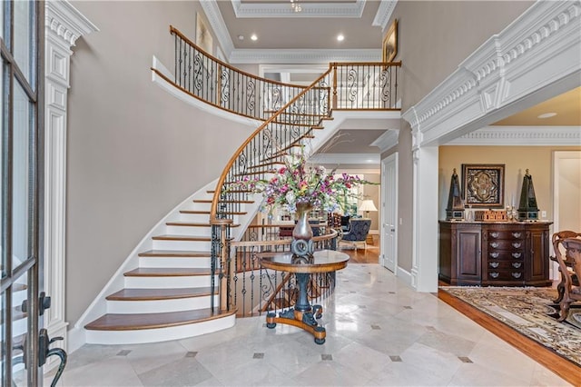 entryway with ornamental molding, baseboards, stairway, and a high ceiling