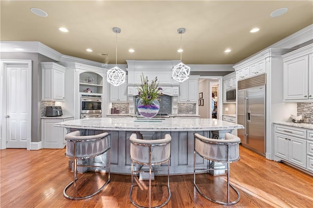 kitchen with a spacious island, a breakfast bar, open shelves, and built in appliances