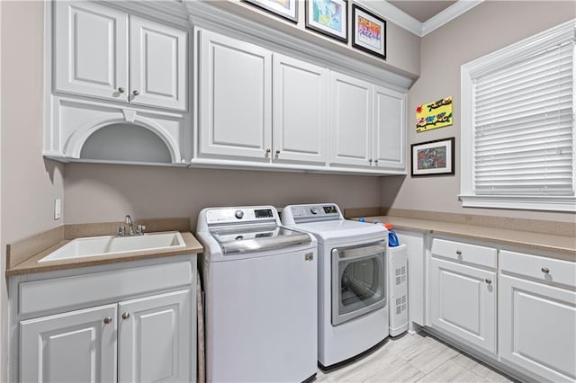 washroom featuring ornamental molding, independent washer and dryer, cabinet space, and a sink