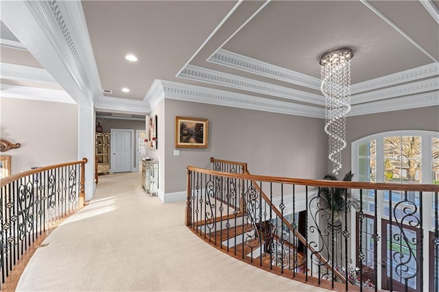 corridor with a chandelier, a raised ceiling, and an upstairs landing