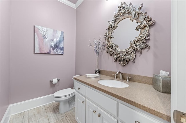 bathroom with toilet, ornamental molding, vanity, and baseboards