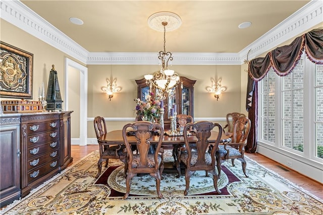 dining area with light wood-style flooring, visible vents, baseboards, an inviting chandelier, and crown molding