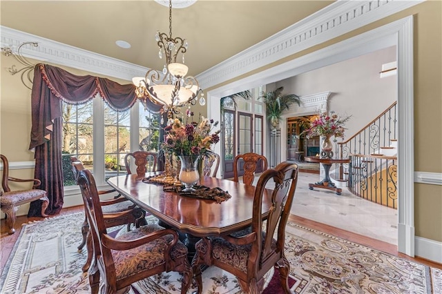 dining space with a chandelier, wood finished floors, stairs, and ornamental molding