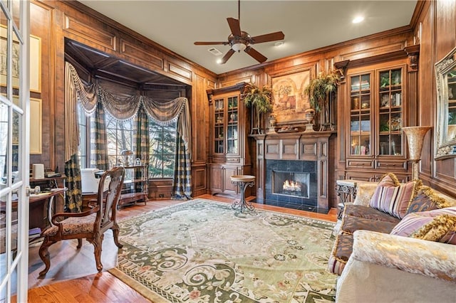 living area featuring wood walls, a fireplace, wood finished floors, and crown molding