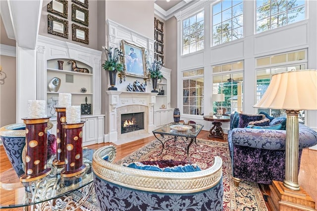 living room with ornamental molding, plenty of natural light, wood finished floors, and built in shelves