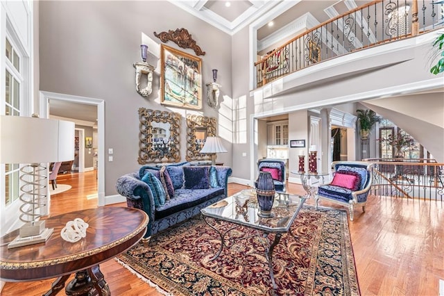 living room featuring a towering ceiling, baseboards, coffered ceiling, and wood finished floors